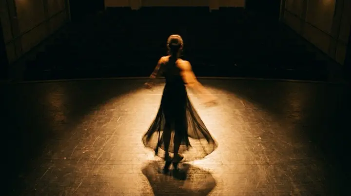A dancer's twirl caught in warm stage light